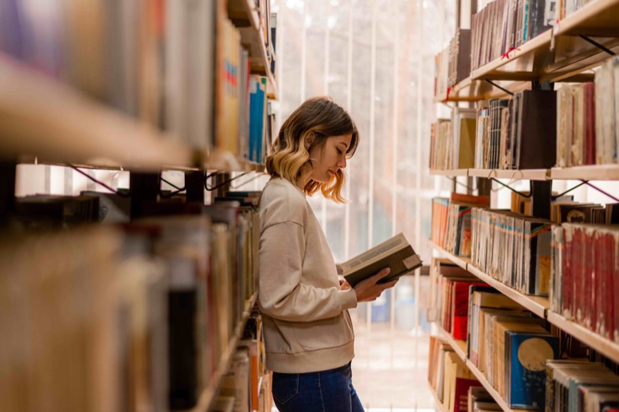 Young person reading in a library, from Children and Screens