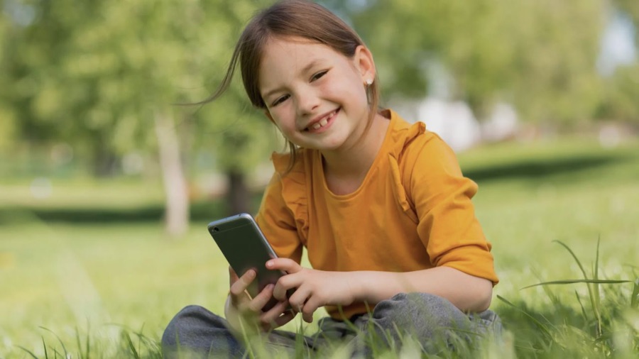 Child holding a phone outdoors, from Protect Young Eyes